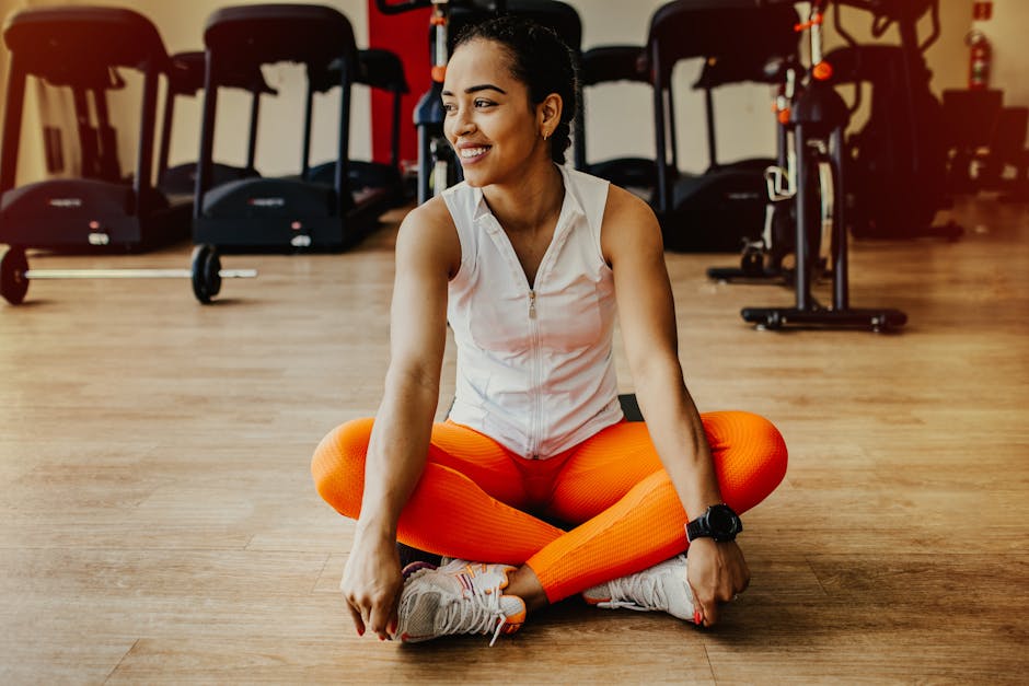 Confident woman in bright workout attire smiling while sitting in a gym
